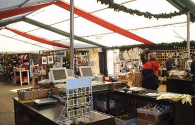 Christmas-themed retail marquee with decorated stalls, tills, and festive stock on display.