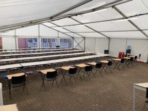 Temporary classroom set up inside a marquee with desks, chairs and whiteboard for school use