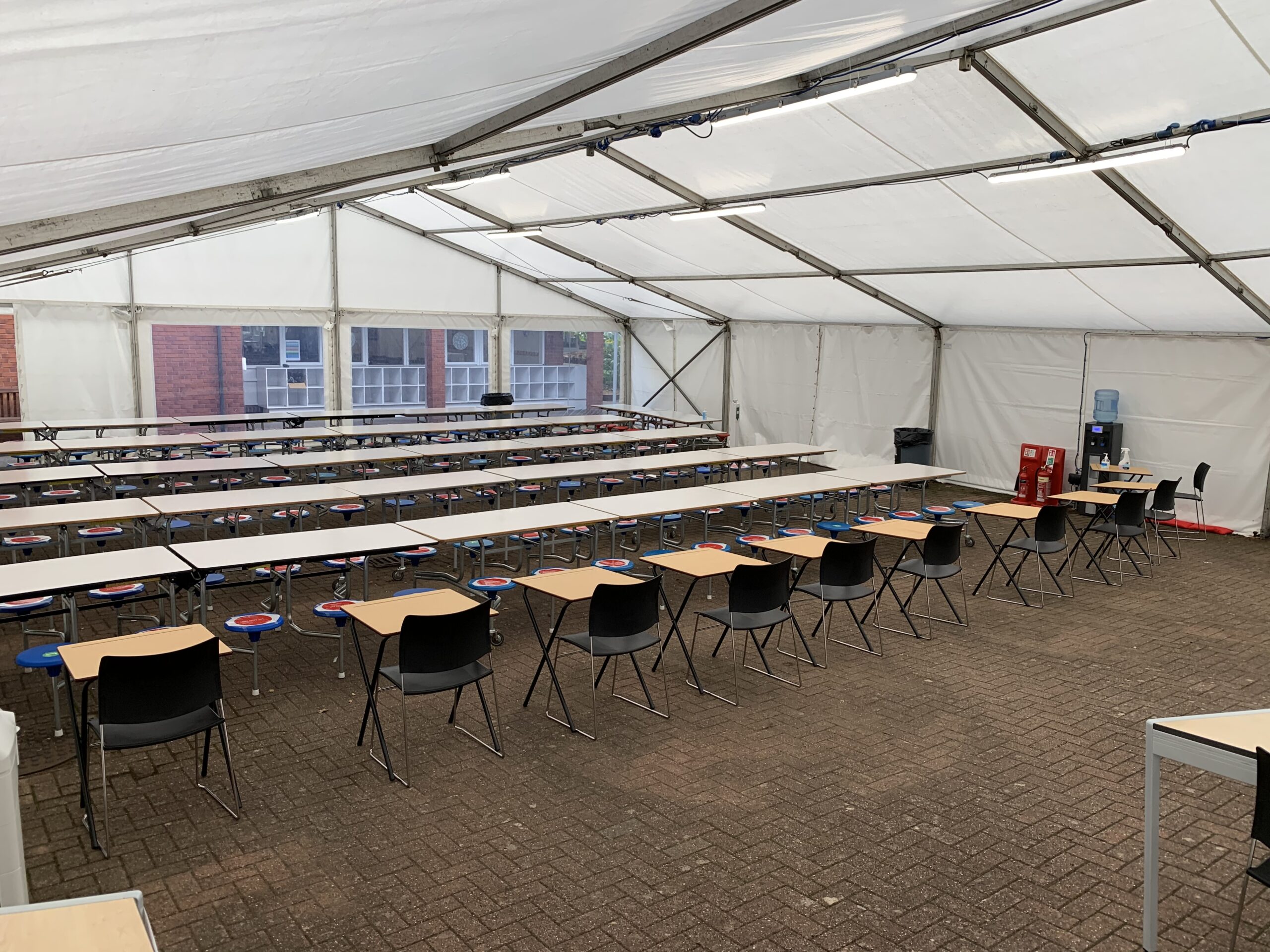 Temporary classroom set up inside a marquee with desks, chairs and whiteboard for school use