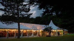 Elegant spring garden marquee with clear roof panels and soft evening lighting set on a country estate lawn in Surrey