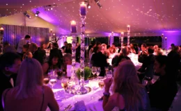 Elegant marquee dinner with candlelit tables, star cloth ceiling, and guests enjoying a formal evening celebration