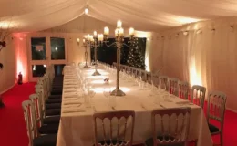 Elegant Christmas marquee with red carpet, long banquet table and candelabra centrepieces.