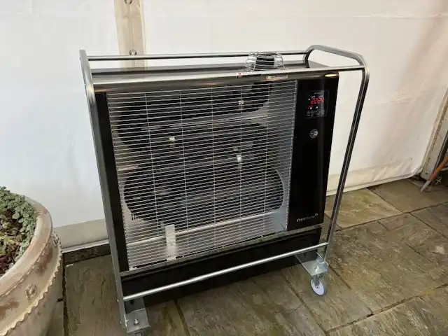 Portable Airrex diesel bio heater positioned inside a marquee next to a potted olive tree for winter heating