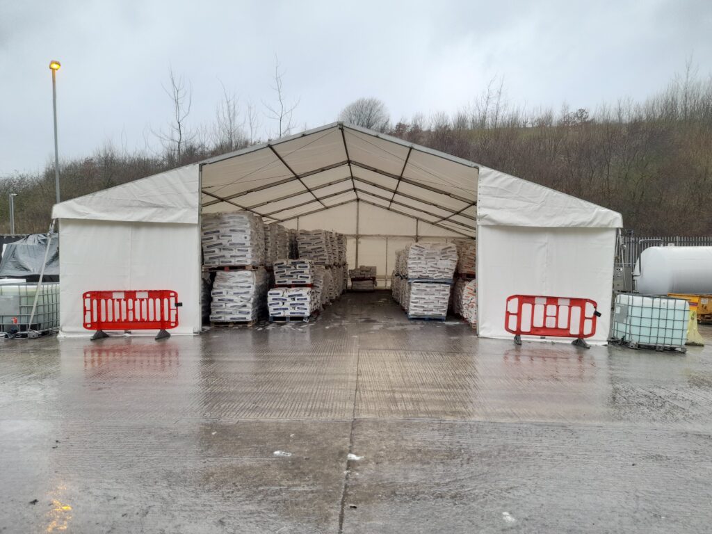 Storage marquee providing secure weatherproof storage for palletised materials at an industrial site during wet weather.