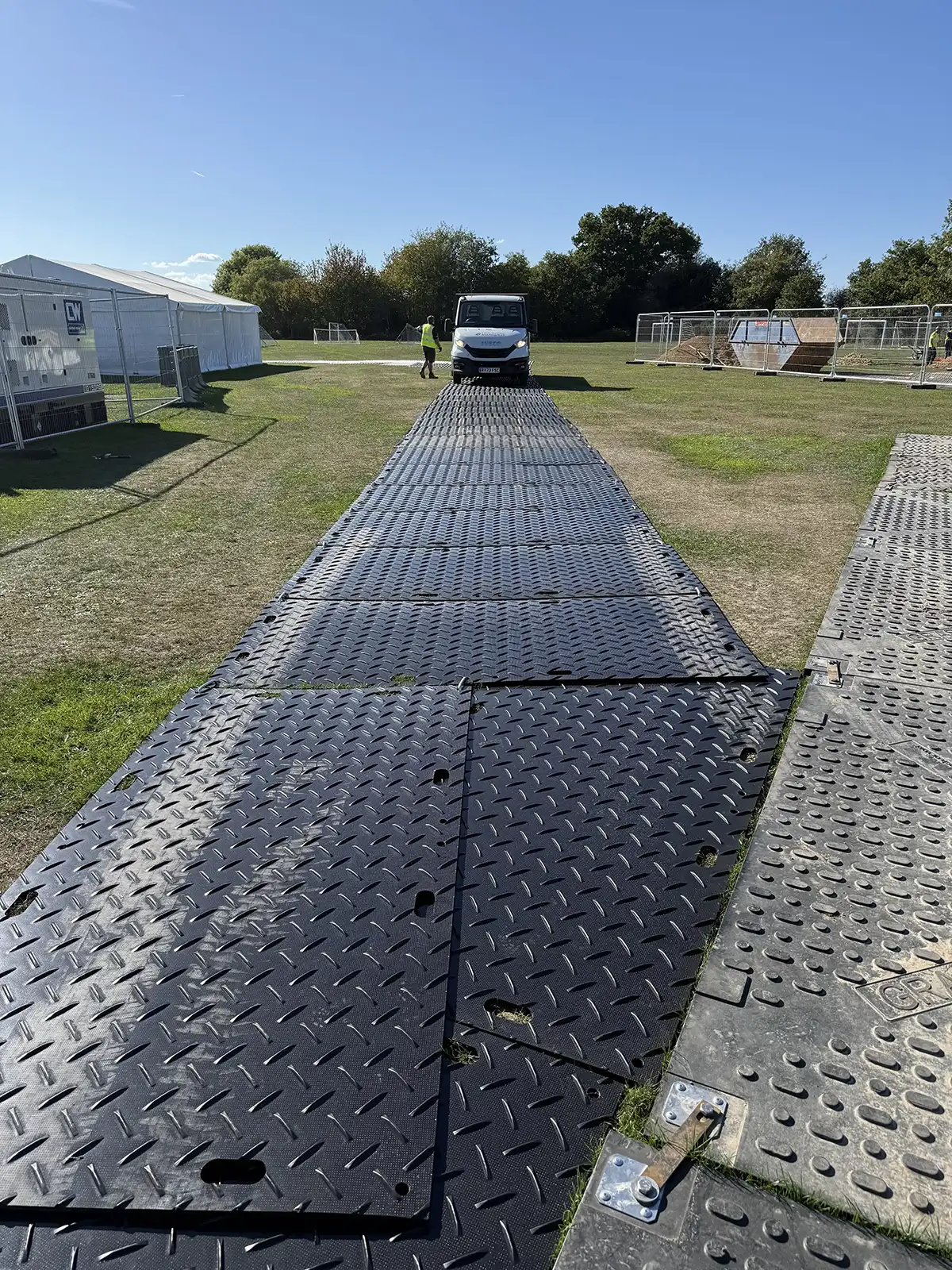Temporary roadway trackway panels installed on grass for vehicle access to marquee site