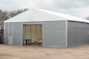 Temporary industrial storage building with steel-clad walls and wide access openings, providing secure weatherproof storage for equipment, vehicles and stock.