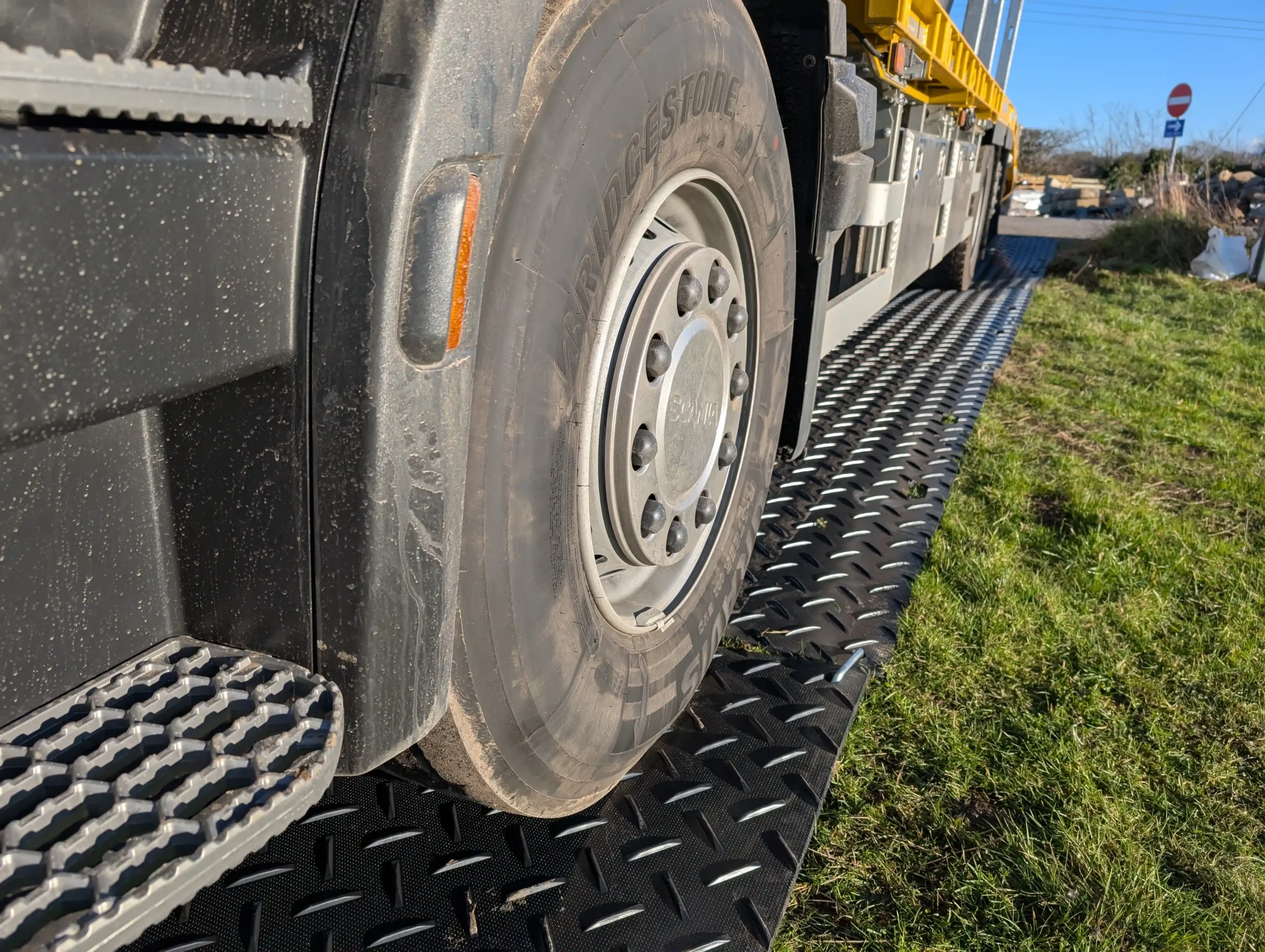 Temporary trackway panels supporting heavy vehicle access on grass, protecting ground from damage on a sensitive site